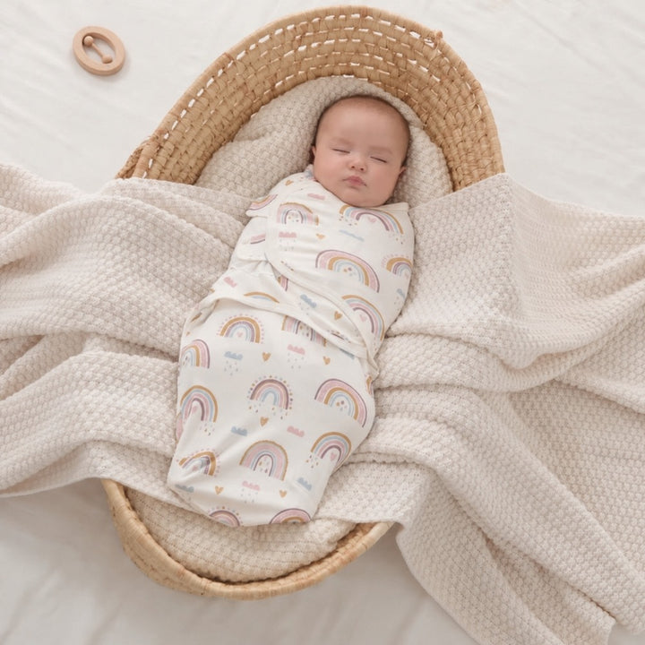 Baby asleep in a woven basket in a rainbow wrap