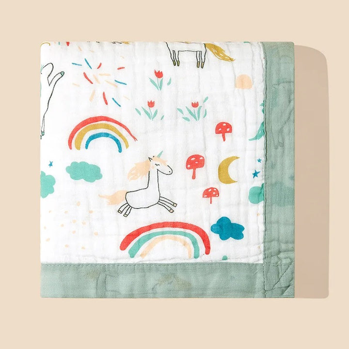 Cotton muslin blanket with unicorn and rainbow print, green bound edge